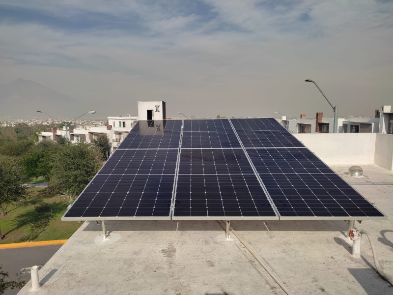 Seis paneles solares sobre la losa plana de una casa en Monterrey, con árboles y casas alrededor